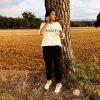 Mujer con la camiseta cristiana GRÀCIA de algodón orgánico, vista de cuerpo entero en un campo
