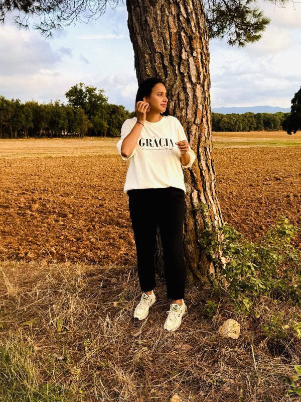 Mujer con la camiseta cristiana GRÀCIA de algodón orgánico, vista de cuerpo entero en un campo