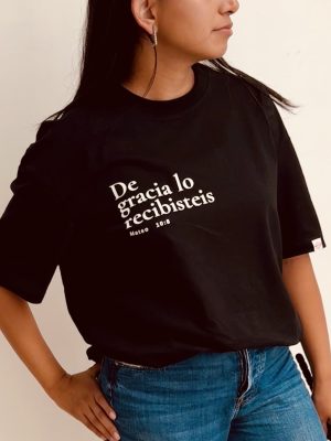 Detalle del estampado De gracia lo recibisteis, Mateo 10:8, en blanco sobre camiseta negra de algodón orgánico