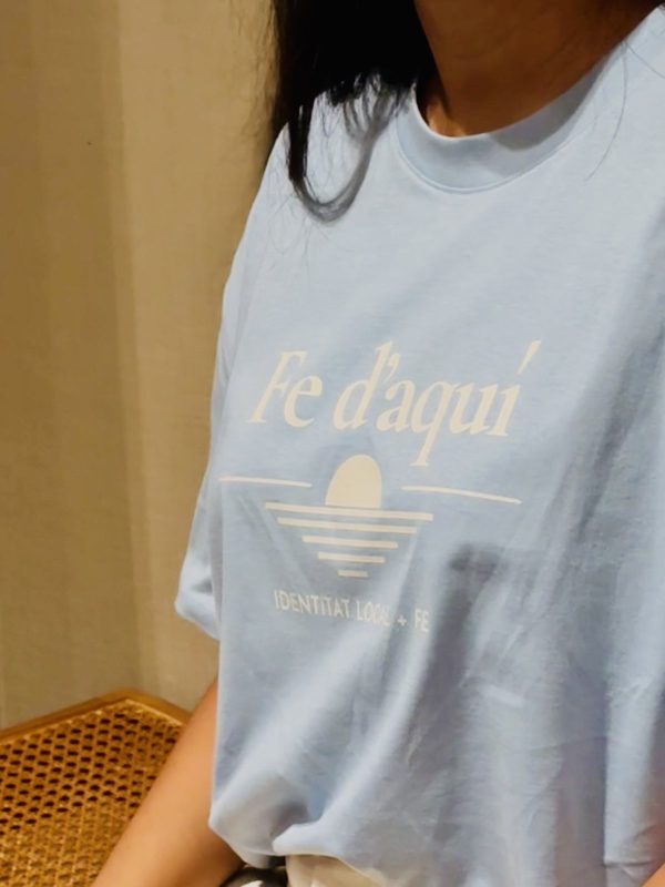 Camiseta Fe d'aquí azul — detalle del tejido Detalle del tejido y la caída de la camiseta Fe d'aquí en azul mediterráneo