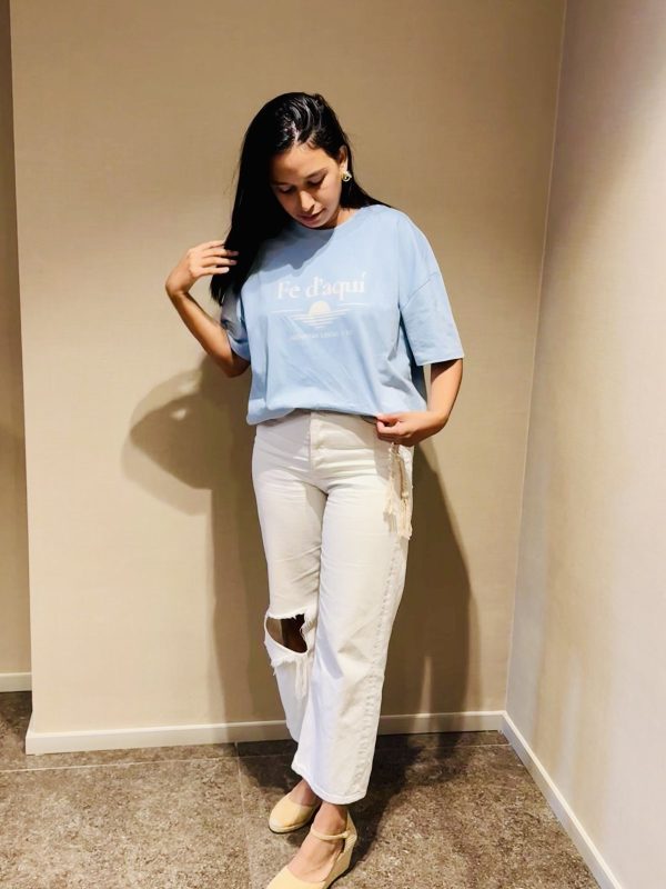 Camiseta Fe d'aquí azul — cuerpo entero Mujer con la camiseta cristiana Fe d'aquí en azul mediterráneo, vista de cuerpo entero