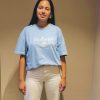Camiseta Fe d'aquí azul — vista frontal Mujer sonriendo con la camiseta cristiana Fe d'aquí en azul mediterráneo