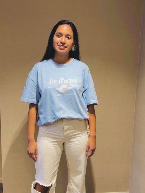 Camiseta Fe d'aquí azul — vista frontal Mujer sonriendo con la camiseta cristiana Fe d'aquí en azul mediterráneo