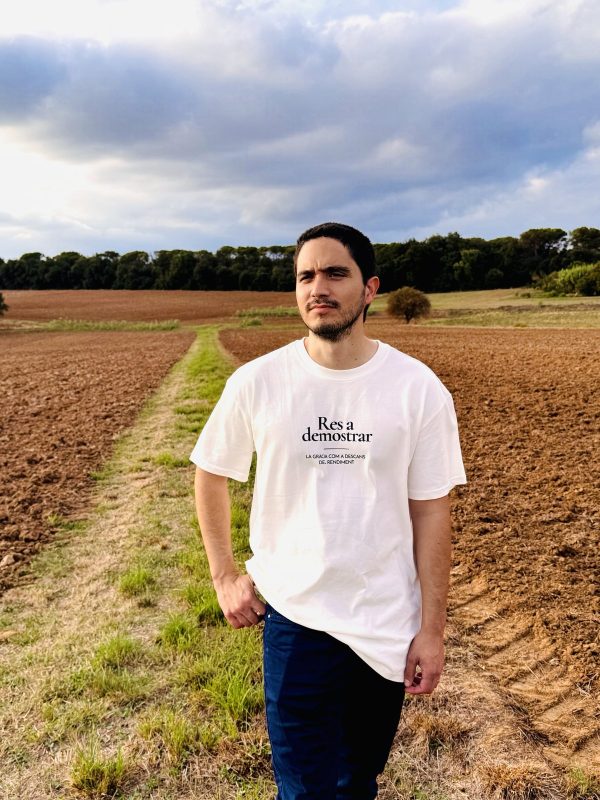Camiseta Res a demostrar — cuerpo entero Hombre con la camiseta cristiana Res a demostrar de algodón orgánico, de cuerpo entero en un campo