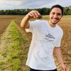 Camiseta Res a demostrar — retrato Hombre sonriendo con la camiseta cristiana Res a demostrar en un campo